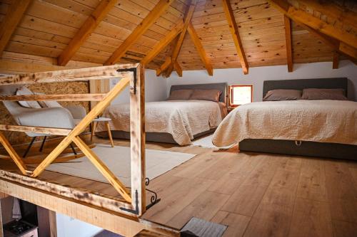a bedroom with two beds and a wooden ceiling at Etno kuca Drina in Loznica