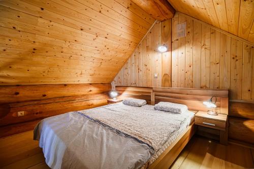 a bedroom with a bed in a wooden cabin at Holiday Home Happiness in Hočko Pohorje