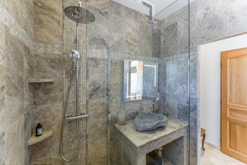 a bathroom with a shower with a glass door at La Bastide Des Mereuilles in Orange