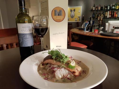 a plate of food on a table with a bottle of wine at Dunster Castle Hotel in Dunster