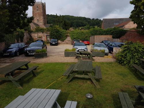 a group of picnic tables in a yard with parked cars at Dunster Castle Hotel in Dunster
