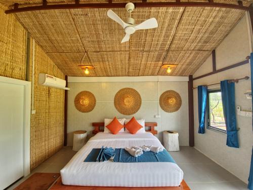 a bedroom with a large bed with a ceiling at Cow Barn Cafe and Lodge Preah Vihear in Phumĭ Nhông