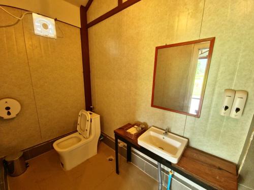 a bathroom with a toilet and a sink at Cow Barn Cafe and Lodge Preah Vihear in Phumĭ Nhông