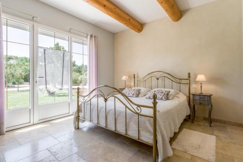 a bedroom with a bed and a large window at La Bastide Des Mereuilles in Orange