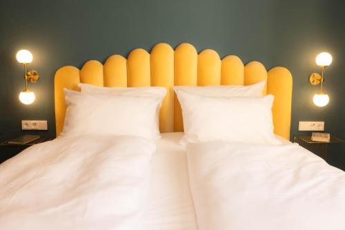 a bed with two white pillows and a yellow headboard at the eighteen86 by keyone in Bad Gastein