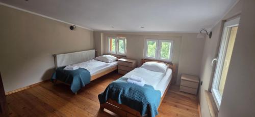 a small bedroom with two beds and two windows at Zacisze Trzech Gór- klimatyczne noclegi i restauracja in Jedlina-Zdrój