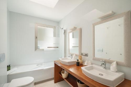 a white bathroom with two sinks and a tub at Can Drago in Ibiza Town
