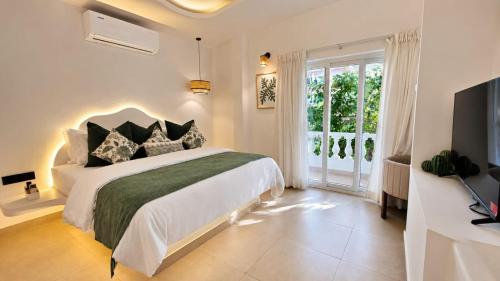 a white bedroom with a large bed and a window at White Coco Luxury Villas, Private Pool, North Goa in Baga