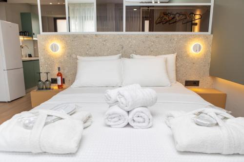 a bedroom with a white bed with towels on it at iMa-Ge Luxury in Nea Vrasna