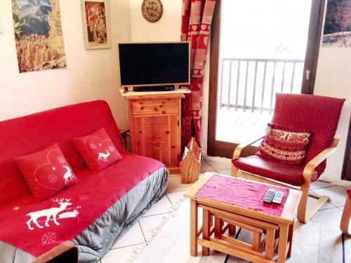 a living room with a red couch and a tv at Appartement spacieux à Le Monêtier-les-Bains - 75 m² avec vue in Le Monêtier-les-Bains