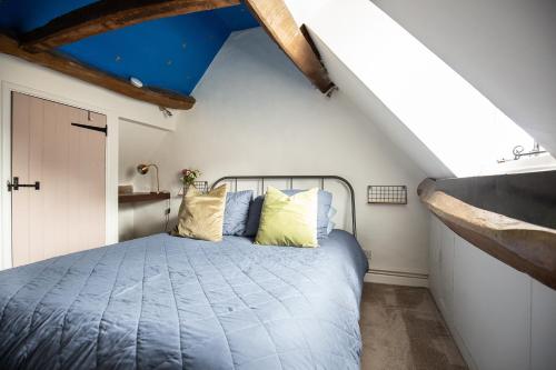 a bedroom with a blue bed in a attic at Cozy Cotswold Burford Cottage in Burford