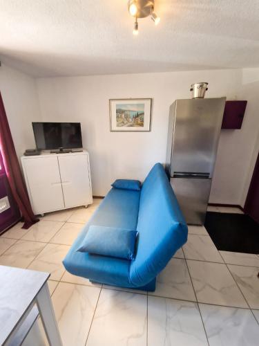 a blue couch in a living room with a refrigerator at Appartement cosy à Gruissan, piscine partagée, 25 m² in Gruissan