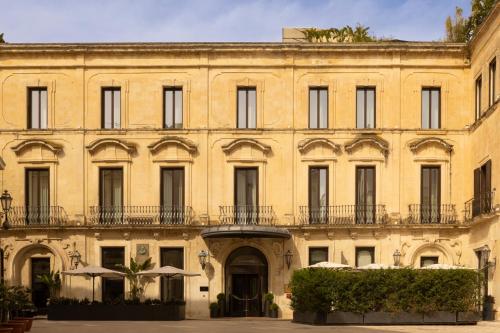 a large yellow building with windows and balconies at Patria Palace Lecce - The Leading Hotels of The World in Lecce