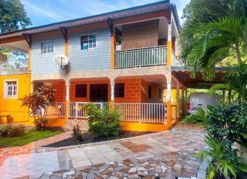a yellow house with a balcony and a driveway at Maison charmante à Pointe Noire, vue montagne, jardin privé in Pointe-Noire