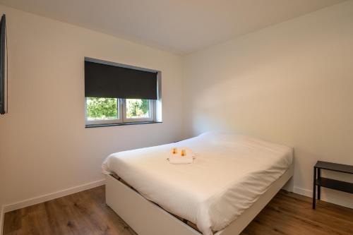 a white bedroom with a bed with a window at Beautiful and spacious renovated home for 10 in Ostend