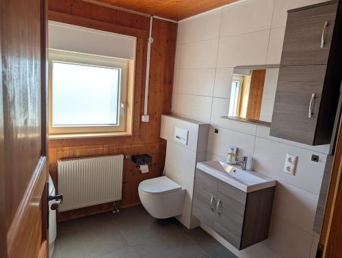 ein Badezimmer mit Toilette, Waschbecken und Fenster in der Unterkunft Gemütlich & einladend in Laufenselden