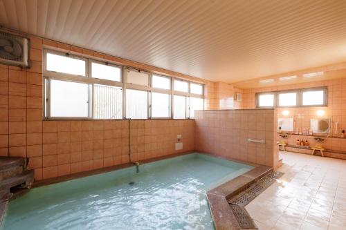 a large pool of water in a room with windows at kkrshirahamamihamasou in Shirahama