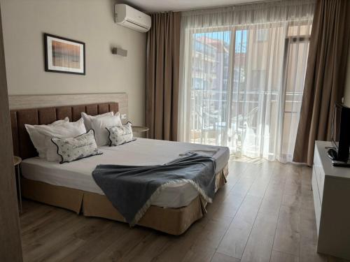 a bedroom with a bed and a large window at Корал, Хотел, Поморие in Pomorie