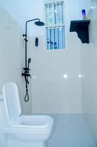 a white bathroom with a toilet and a window at Ray Infinity Suites in Paje