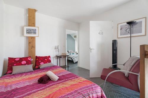 a bedroom with a large bed and a chair at Joli Duplex Centre-ville 5km Dinard in Pleurtuit