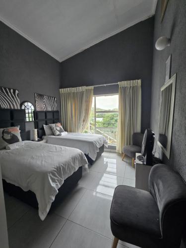 a bedroom with two beds and a chair and a window at The Calm Views Holiday Home in Hazyview