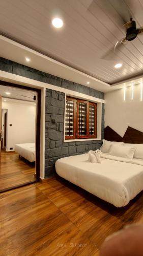 a bedroom with two beds and a brick wall at Birdwing Cottage, Munnar in Munnar