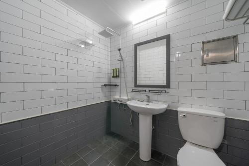 a white bathroom with a toilet and a sink at EL Hotel in Yangyang