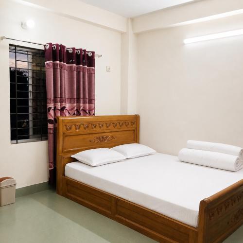 a bedroom with a wooden bed and a window at Jannat Residential Hotel in Atgaon