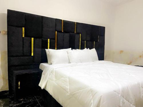 a bedroom with a large white bed with a black headboard at Golden fortune Hotel apartment in Molyko