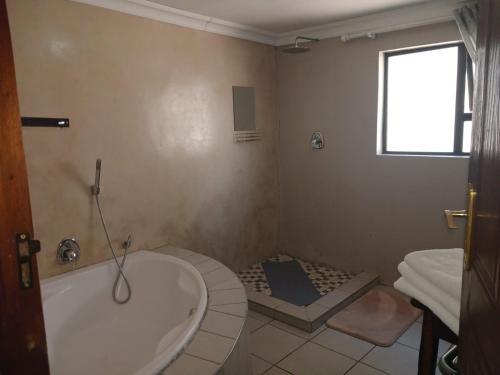 a bathroom with a tub and a sink and a window at African Moon Corporate House in Kempton Park