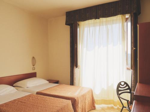 a hotel room with two beds and a window at Hotel Palazzo dei Priori in Siena