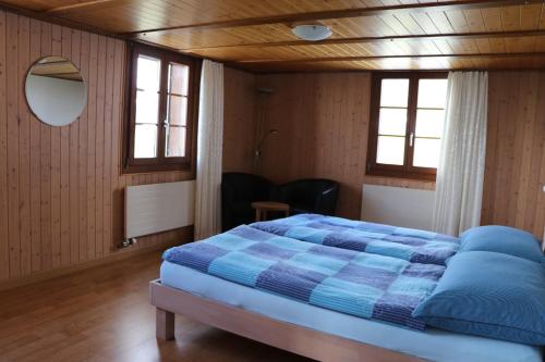 a bedroom with a blue bed and two windows at Naturfreunde in Hergiswil