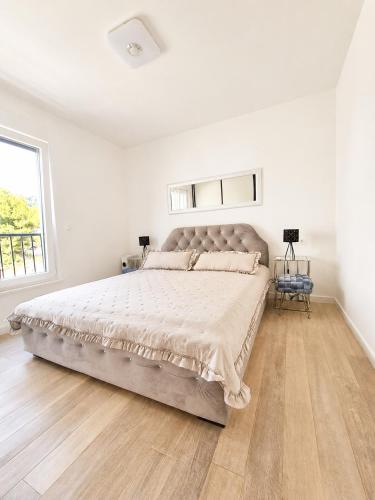 a white bedroom with a large bed and a window at Miami in Veliko Brdo