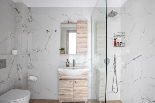 a white bathroom with a sink and a shower at A&E Cretan Oasis in Loutra