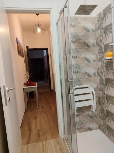 a glass shower door with a white chair in a room at Casa Patrik in Pietra Ligure