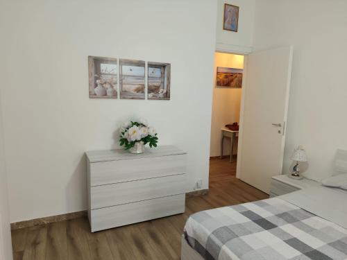 a bedroom with a dresser with a vase of flowers on it at Casa Patrik in Pietra Ligure