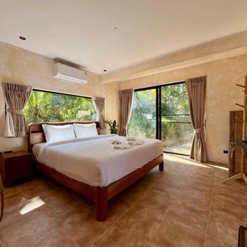 a bedroom with a large bed and large windows at Arcana Wellness Center - Adults Only in Ko Phangan