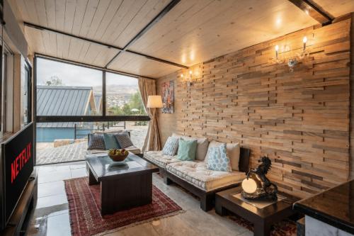 a living room with a couch and a brick wall at Maison Jwar - Charming Caravan Experience - Unique Summer Getaway in Jiwār al Ḩawz
