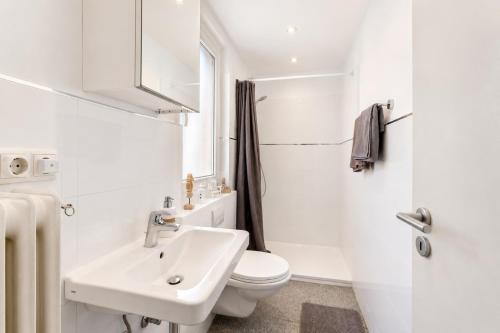 a white bathroom with a sink and a toilet at Charmante Stadtwohnung im Zentrum in Wiesbaden