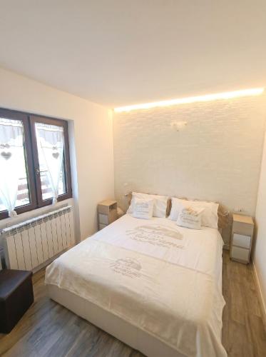 a bedroom with a large white bed with two windows at Casa Panorama Intelvi - Como & Lugano Lakes in Laino