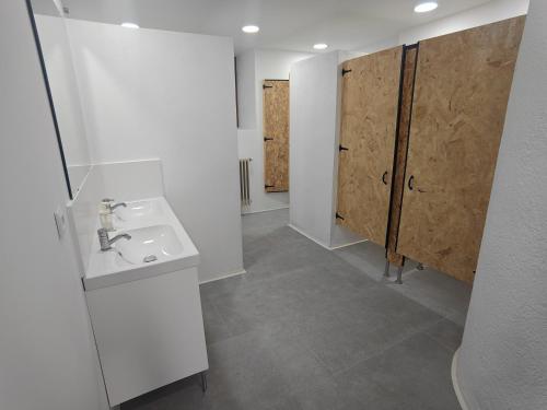 a white bathroom with a sink and wooden doors at Colònies Cadí - Cal Caló in Bellver de Cerdanya