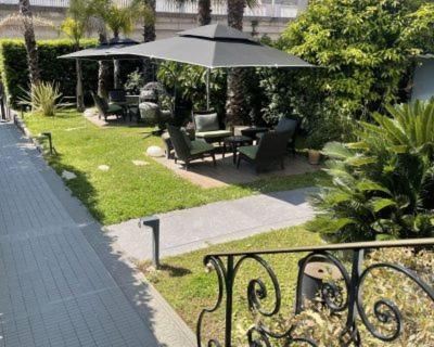 a patio with chairs and an umbrella on the grass at Villa Pruly Hotel Cannes Centre in Cannes