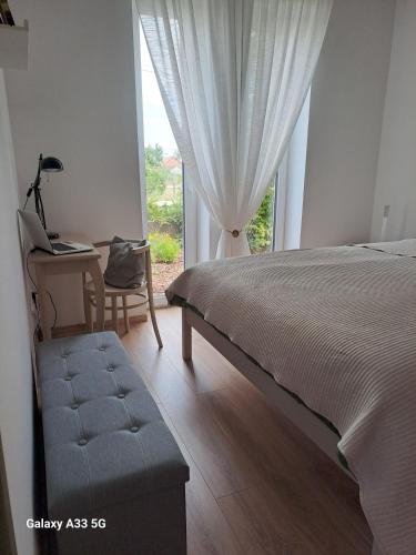 a bedroom with a bed and a desk and a window at Garden House in Dég