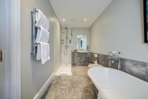 a white bathroom with a tub and a shower at Grosvenor Hotel in Stratford-upon-Avon