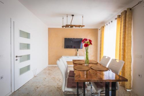 a dining room with a table with a vase of flowers on it at Villa Enigma in Gevgelija