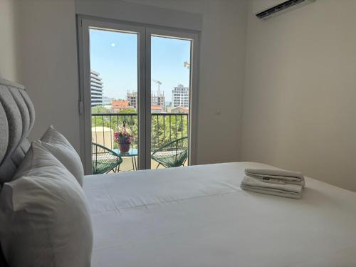 a white bed with a view of a balcony at Olive Šušanj Apartment in Bar
