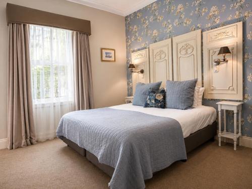 a bedroom with a bed with blue walls and a window at Twelve on Albert in Beechworth