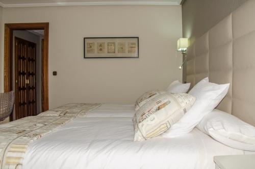 a white bed with white pillows on top of it at Hotel Presa in Riaño