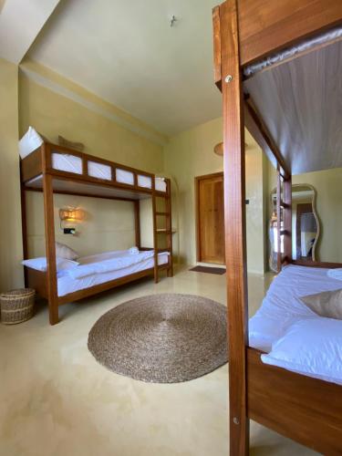 a bedroom with two bunk beds and a rug at Surf'n Lanka - Surf School in Weligama