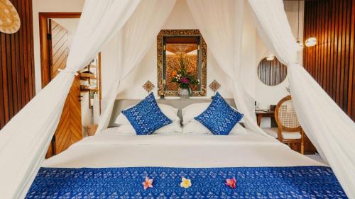 a bedroom with a white bed with blue pillows at Natya Hotel Tanah Lot in Tanah Lot